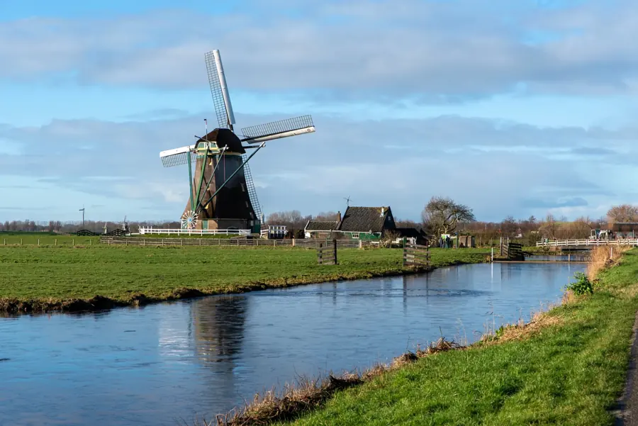A windmill beside a canal in a flat green polder
