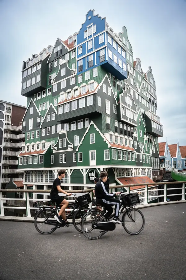 Two cyclists in front of a hotel in Zaandam built from stacked green Zaan houses